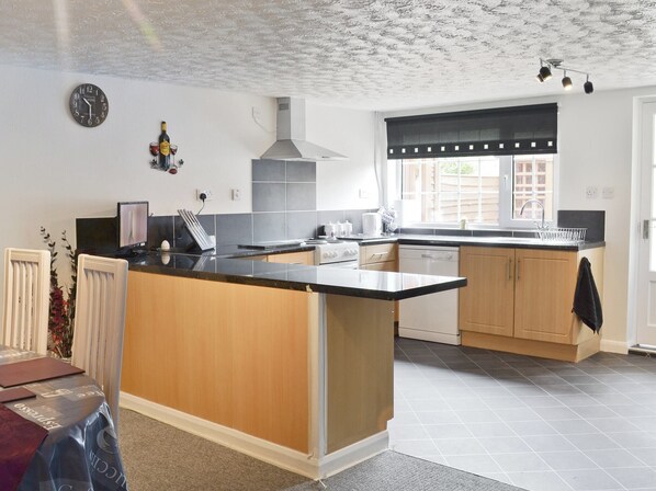 A modern kitchen with a central island, a built-in oven, and a window with a black valance.