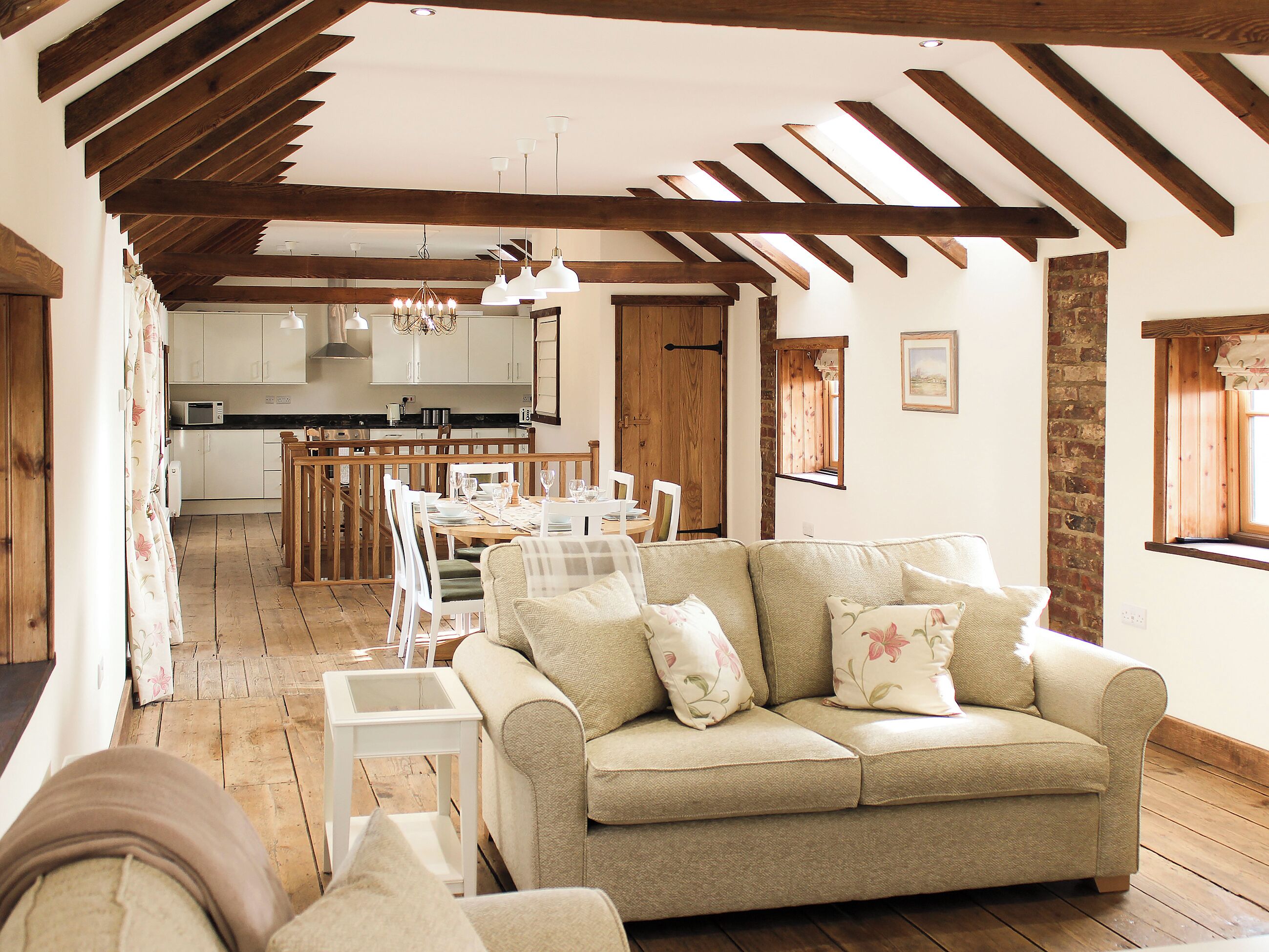 A spacious living area with a sofa, dining table, and kitchen in the background.