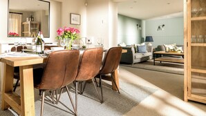 Una sala de estar moderna con comedor, que presenta una mesa de madera, sillas de cuero y un sofá.