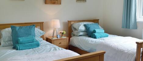 Two twin beds with wooden headboards, white bedding, and teal pillows.