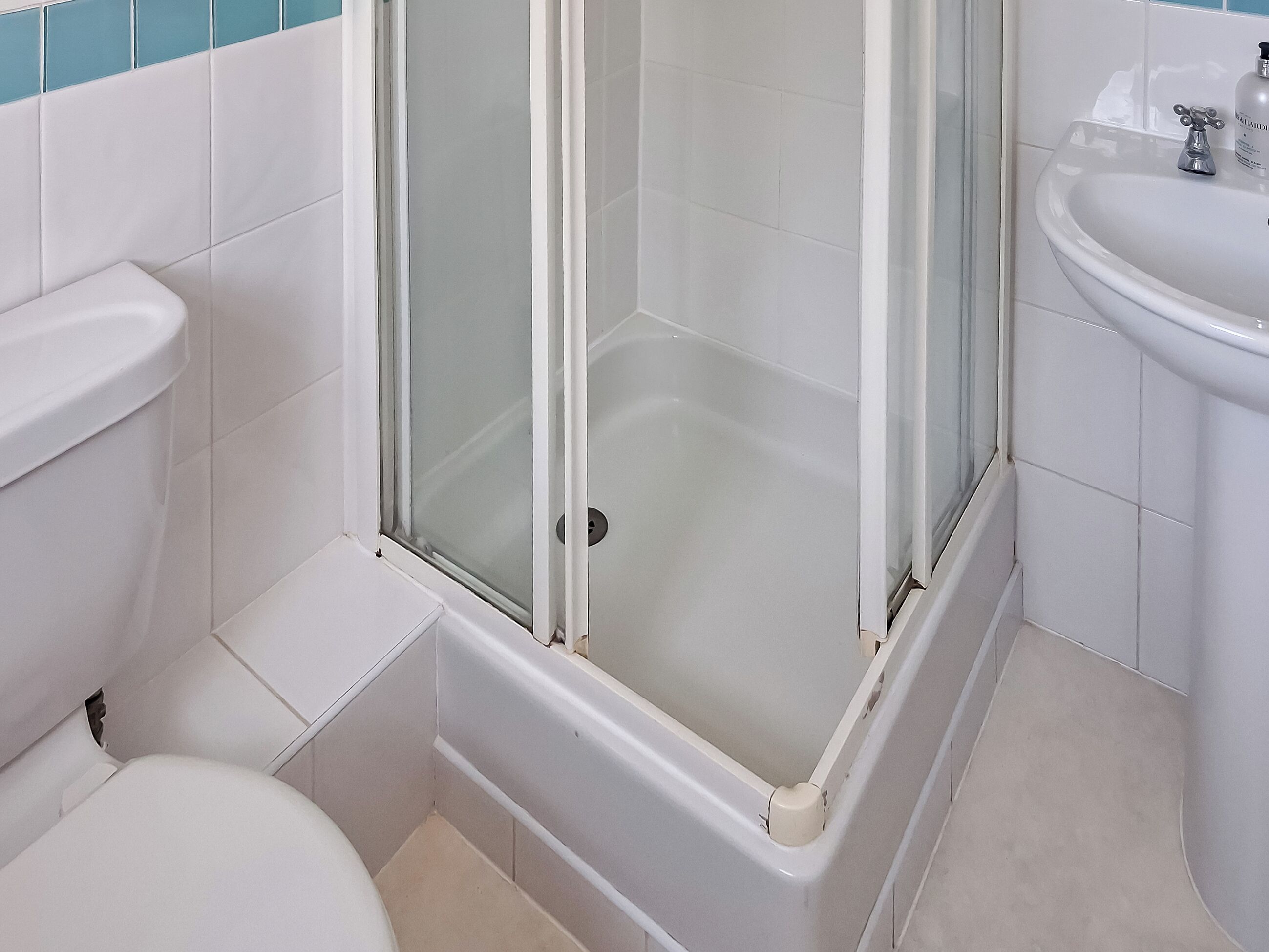 Een badkamer met douche, toilet en wastafel.