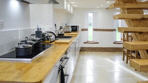 A modern kitchen with wooden countertops, stainless steel appliances, and a view of the outdoors through a window.