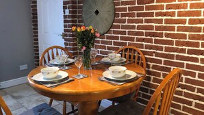 Een eettafel gedekt voor vier personen, met kommen en wijnglazen met een bloemenprint, omringd door houten stoelen met beklede zitplaatsen.