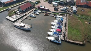 Un port de plaisance avec des bateaux amarrés, un quai et des bâtiments en arrière-plan.