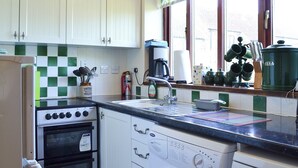 A kitchen with white cabinets, a stove, a washing machine, and a window with a view of the outside. - 3 bedroom accommodation in Laytham, near York (Laytham, near York)