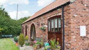 A brick house with a tiled roof, a front porch with potted plants, and a garden path. - 3 bedroom accommodation in Laytham, near York (Laytham, near York)