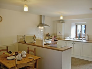 A kitchen with a wooden table, white cabinets, and a window. - 2 bedroom accommodation in Rhos, near Pontardawe (Rhos, near Pontardawe)