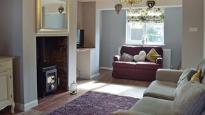 A living room with a fireplace, a sofa, a television, and a chandelier. - 2 bedroom accommodation in Pakefield, near Lowestoft (Pakefield, near Lowestoft)