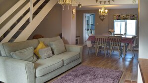 A living room with a sofa, a dining table with chairs, a chandelier, and a staircase. - 2 bedroom accommodation in Pakefield, near Lowestoft (Pakefield, near Lowestoft)