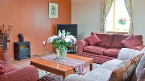 Ein Wohnzimmer mit einer Couch, einem Couchtisch aus Holz, einem Fernseher und einem Kamin.