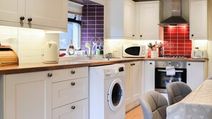 A modern kitchen with white cabinets, a washing machine, a microwave, and a stove. - 2 bedroom accommodation in Llandygai, near Bangor (Llandygai, near Bangor)