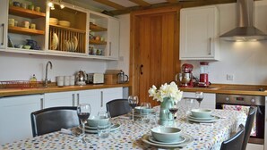 Una cocina con vigas de madera, armarios blancos y un mantel estampado con lunares.