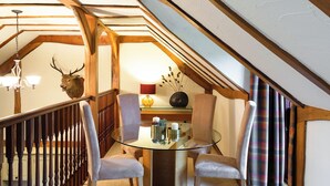 A dining area with a glass table, two chairs, a chandelier, and a deer head mounted on the wall. - 2 bedroom accommodation in Kinross, near Perth (Kinross, near Perth)