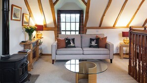 A cozy living room with a sofa, a glass coffee table, a fireplace, and wooden beams on the ceiling. - 2 bedroom accommodation in Kinross, near Perth (Kinross, near Perth)