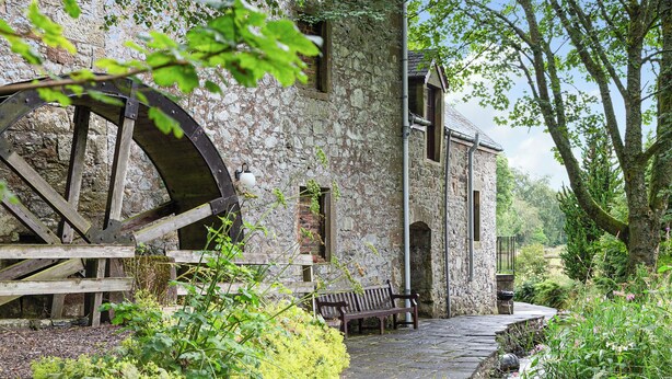 A stone building with a large water wheel, a bench, and a pathway surrounded by greenery. - 2 bedroom accommodation in Kinross, near Perth (Kinross, near Perth)