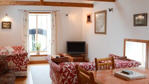 A cozy living room with a wooden ceiling, a television, and a dining table with chairs. - 2 bedroom accommodation in John O&rsquo; Groats (John O&rsquo; Groats)
