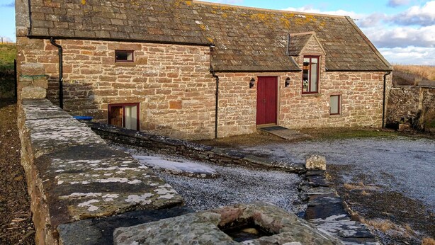 A stone building with a red door, a small window, and a chimney. - 2 bedroom accommodation in John O&rsquo; Groats (John O&rsquo; Groats)