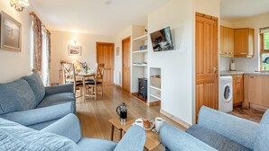 A modern living room with a sofa, a coffee table, and a dining area with a table and chairs. - 2 bedroom accommodation in Achnamara, near Lochgilphead (Achnamara, near Lochgilphead)
