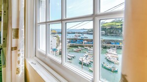 A bay with multiple boats docked, a clear sky, and a view of the coastline through a window with white frames.