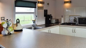A kitchen with a window, sink, toaster, stove, and a sign on the wall. - 3 bedroom accommodation in Bridge of Dee, near Castle Douglas (Bridge of Dee, near Castle Douglas)