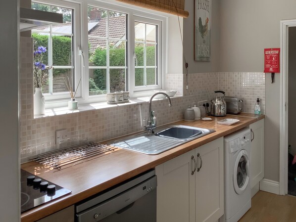 A modern kitchen with a built-in dishwasher, a sink, and a window with a view of the outside.