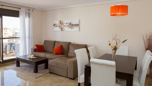 Ein modernes Wohnzimmer mit einer Couch, einem Couchtisch, einem Esstisch, Stühlen und einem Gemälde an der Wand.
