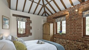 Une chambre à coucher avec un lit, des poutres en bois, des murs en briques, une armoire en bois et une fenêtre donnant sur un paysage agréable.