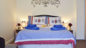 A neatly made bed with blue and white checkered bedding, two rolled towels, and a wall decoration above it. - 1 bedroom accommodation in Pevensey Bay, near Eastbourne (Pevensey Bay, near Eastbourne)