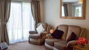 A living room with two armchairs, a small table with a vase of flowers, a lamp, and a mirror on the wall. - 1 bedroom accommodation in Pevensey Bay, near Eastbourne (Pevensey Bay, near Eastbourne)