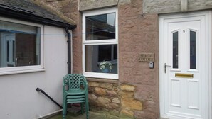 A stone building with a white door marked '9' and a sign reading 'SHAFTO COTTAGE'. - An affordable terraced cottage just 50 yards from the harbour at Seahouses. (Seahouses, near Bamburgh)