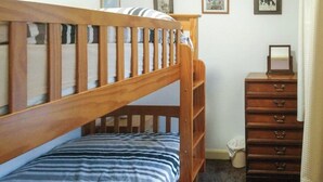 A bedroom with a wooden bunk bed, a dresser with drawers, and framed pictures on the wall. - An affordable terraced cottage just 50 yards from the harbour at Seahouses. (Seahouses, near Bamburgh)