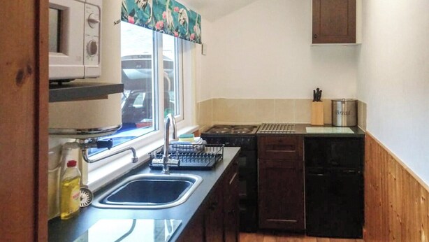 A compact kitchen with a sink, a microwave, and a toaster. - An affordable terraced cottage just 50 yards from the harbour at Seahouses. (Seahouses, near Bamburgh)