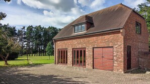 Een gebouw van baksteen met een schuin dak, twee grote garage deuren en een klein raam.