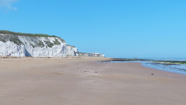 Une plage bordée de falaises blanches, sous un ciel dégagé.