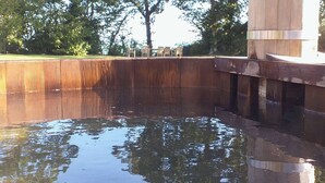 Una piscina circondata da alberi e da un'area verde, su un molo di legno.