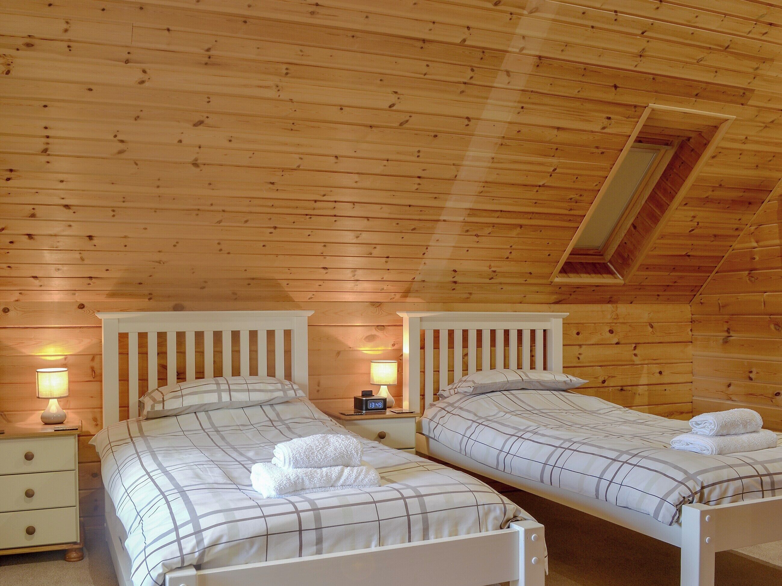 Et værelse med to senge, trævægge og et skråt loft.