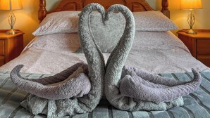 Ein Bett mit einer herzförmigen Handtuch-Arrangement, einem Holzkopfschild und zwei Nachttischlampen.