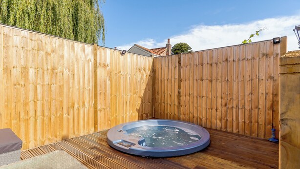 Ein Whirlpool in einem Garten mit Holzzaun und einer Holzterrasse.