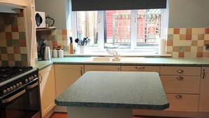 Una cocina con estufa a gas, un lavamanos y una ventana que da a una cerca roja.