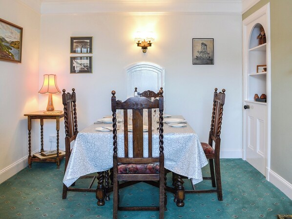 Ein Esszimmer mit einem für vier Personen gedeckten Tisch, umgeben von Holzstühlen mit geschnitzten Details.