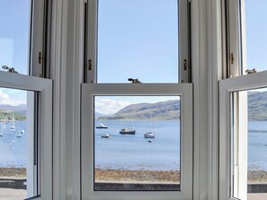 Blick durch ein Fenster auf Boote auf einem See, umgeben von Hügeln.