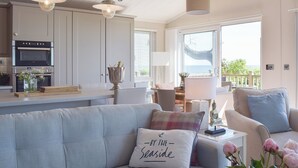 A modern kitchen with built-in appliances, a dining area with a table and chairs, and a view of the outdoors. - 2 bedroom accommodation in Corton, near Lowestoft (Corton, near Lowestoft)