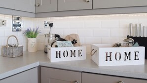 A kitchen counter with two 'HOME' signs, a basket, a plant, a kettle, and a coffee maker. - 2 bedroom accommodation in Corton, near Lowestoft (Corton, near Lowestoft)