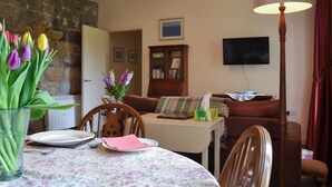 A dining area with a table set for two, a vase of tulips, and a lamp. - 2 bedroom accommodation in Brancepeth, near Durham (Brancepeth, near Durham)
