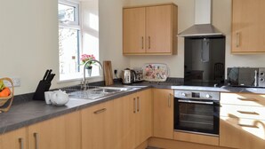 Eine moderne Küche mit Holzausstattung, einer Edelstahl-Spüle, einem Toaster und einem Backofen.