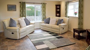Ein Wohnzimmer mit zwei hellbeigen Sofas, einem gestreiften Teppich und einem kleinen Holztisch.