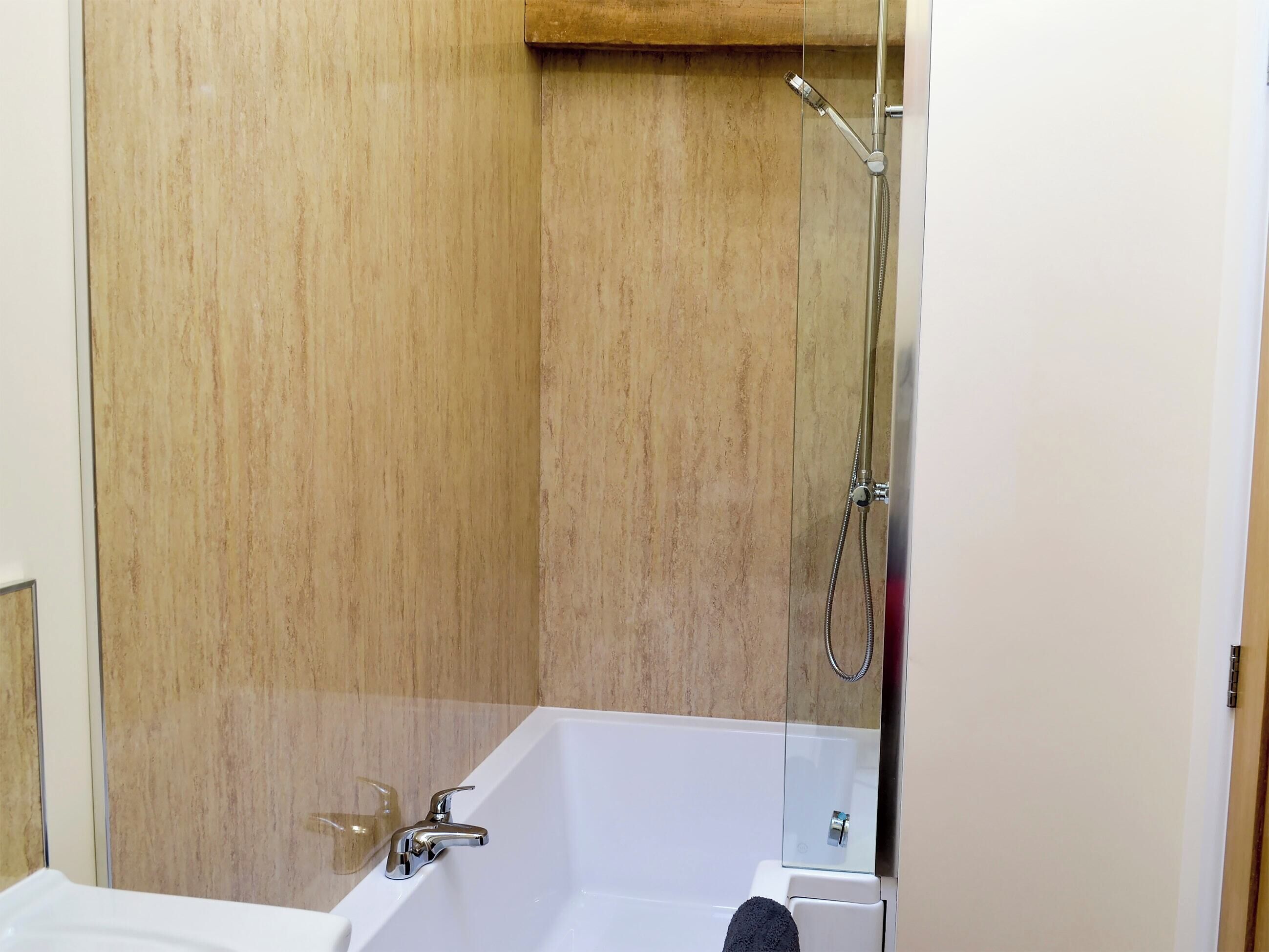 Une salle de bain moderne avec une douche à parois de verre, une baignoire blanche et un lambris en bois sur les murs.