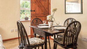 Comedor con mesa de madera dispuesta para cuatro personas, rodeado de sillas tapizadas.