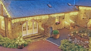 A stone building with a sloped roof, arched windows, and a paved driveway.