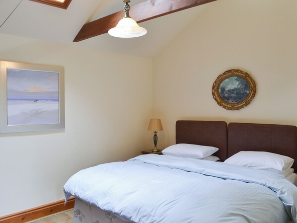 Une chambre à coucher avec un lit, un tableau, une photographie encadrée et un ventilateur de plafond.